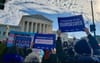 People are holding signs outside of the Supreme Court building such as: "Protect Trans Youth", "Freedom To Be Who I Am" and "Freedom To Be Ourselves"